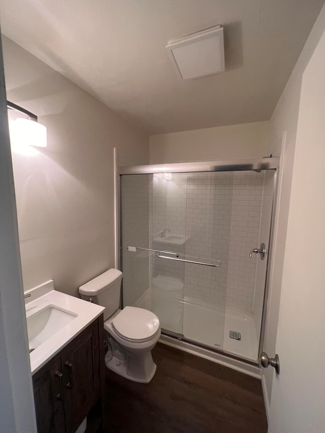 bathroom with wood-type flooring, vanity, toilet, and a shower with door