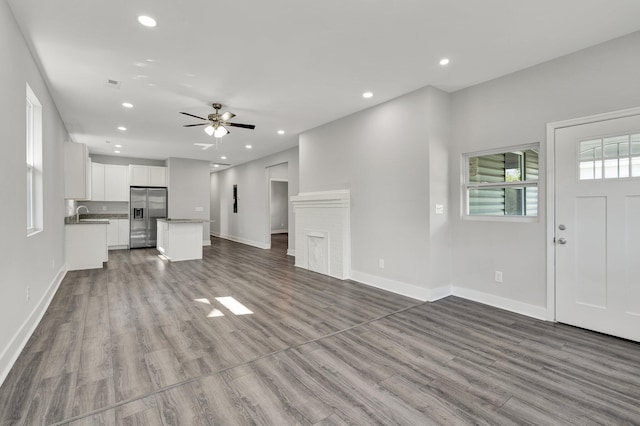 unfurnished living room with sink, light hardwood / wood-style flooring, and ceiling fan