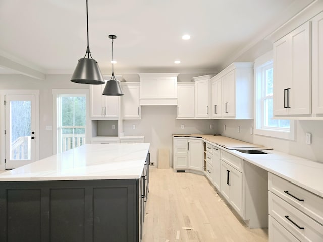 kitchen with light stone counters, a center island, and white cabinets