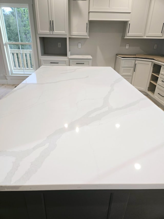 kitchen featuring light stone counters and white cabinets