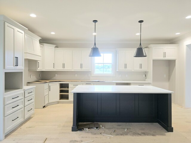 kitchen featuring decorative light fixtures, a center island, light hardwood / wood-style flooring, and white cabinets