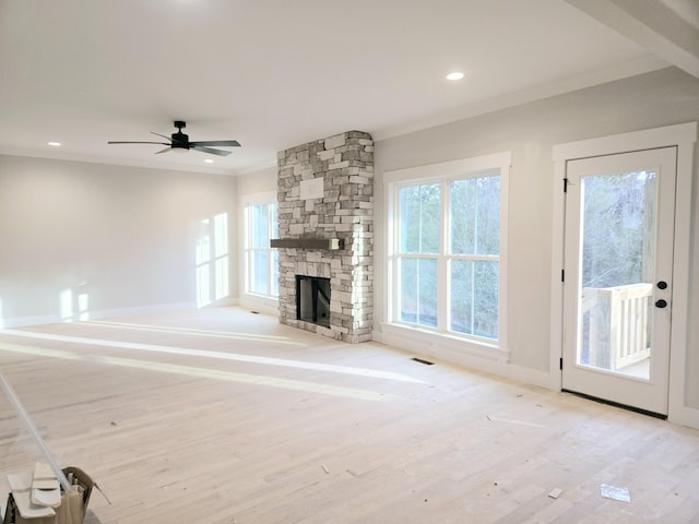 unfurnished living room with ornamental molding, ceiling fan, a fireplace, and light wood-type flooring