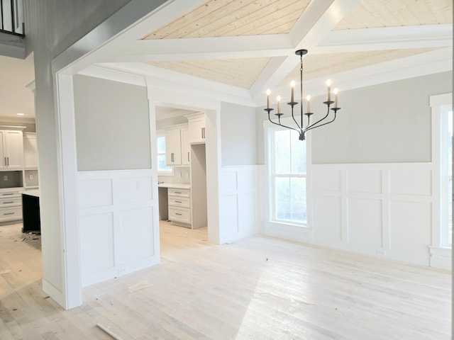 unfurnished dining area featuring light hardwood / wood-style flooring, a chandelier, and beamed ceiling