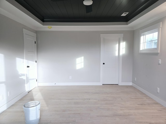 spare room featuring wood ceiling, a tray ceiling, and light wood-type flooring