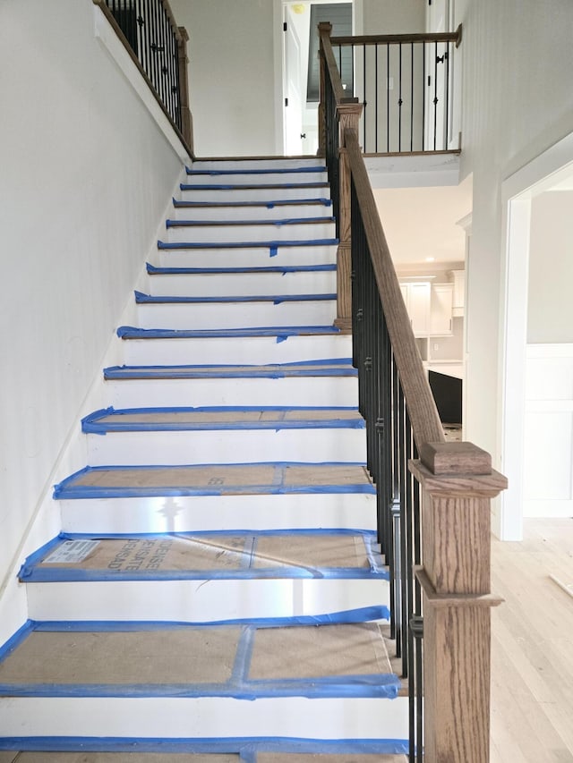 staircase featuring a high ceiling and hardwood / wood-style floors