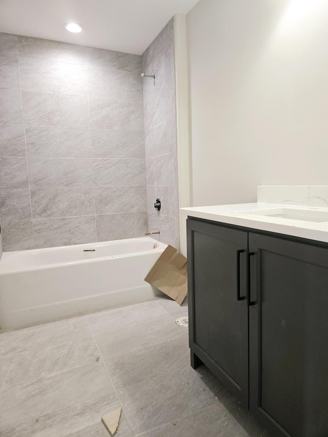 bathroom featuring tiled shower / bath, vanity, and tile patterned flooring