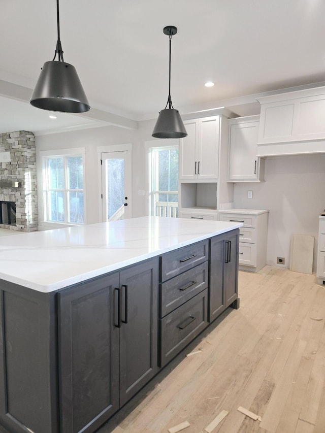 kitchen featuring hanging light fixtures, white cabinets, and light wood-type flooring