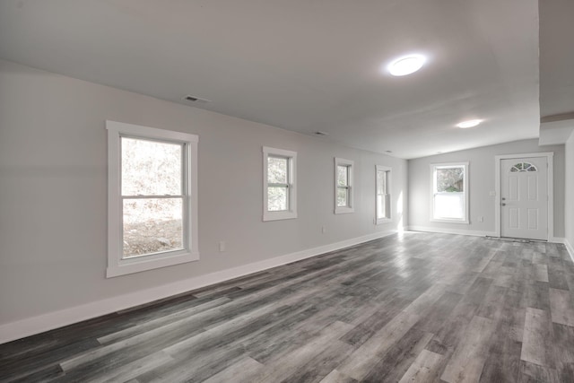 unfurnished room featuring a wealth of natural light, lofted ceiling, and hardwood / wood-style floors