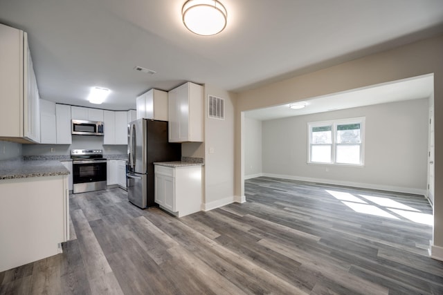 kitchen featuring stainless steel appliances, white cabinetry, light stone counters, and light wood-type flooring