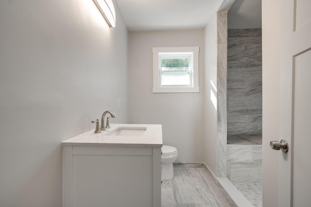 bathroom featuring vanity, toilet, and tiled shower