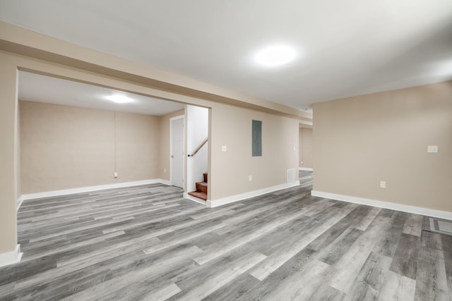 basement with electric panel and light hardwood / wood-style flooring