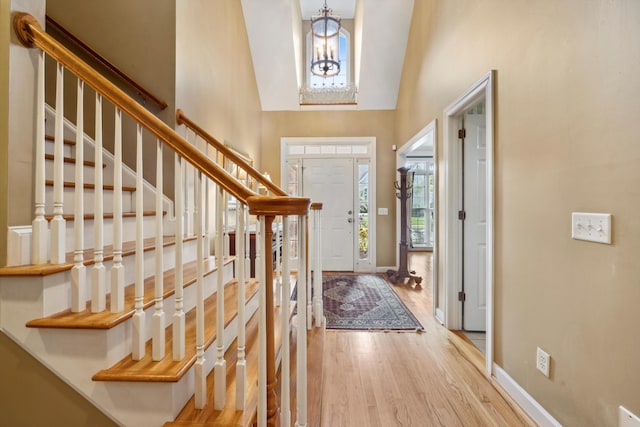 entryway with light hardwood / wood-style flooring, a notable chandelier, and high vaulted ceiling