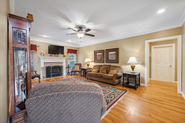 living room featuring ceiling fan, a fireplace, light wood-type flooring, and ornamental molding