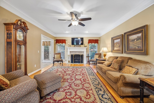 living room with light hardwood / wood-style flooring, ceiling fan, a fireplace, and crown molding