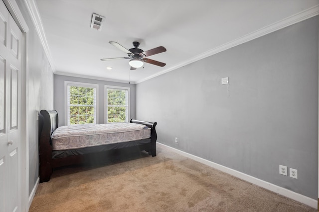 carpeted bedroom featuring ceiling fan, a closet, and crown molding