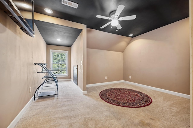 workout area with ceiling fan, light colored carpet, and lofted ceiling