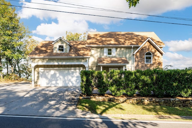 view of front facade featuring driveway, roof with shingles, and an attached garage