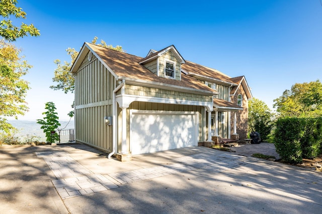 view of front of house with board and batten siding, concrete driveway, an attached garage, and a shingled roof