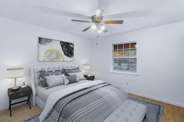 bedroom with a textured ceiling, hardwood / wood-style flooring, and ceiling fan