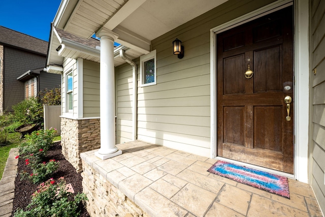 view of exterior entry featuring stone siding and a porch