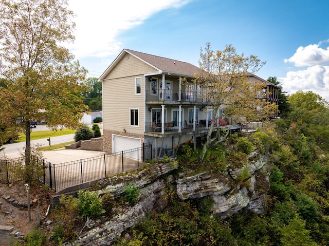 back of house with a balcony, fence private yard, an attached garage, and concrete driveway