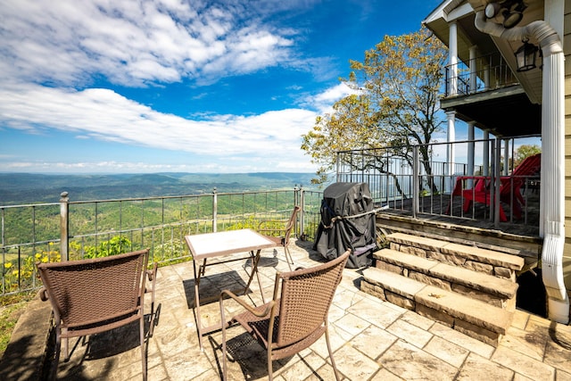 view of patio with a mountain view, area for grilling, and a balcony