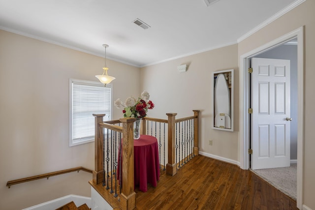 hall featuring visible vents, ornamental molding, dark wood-style flooring, and an upstairs landing