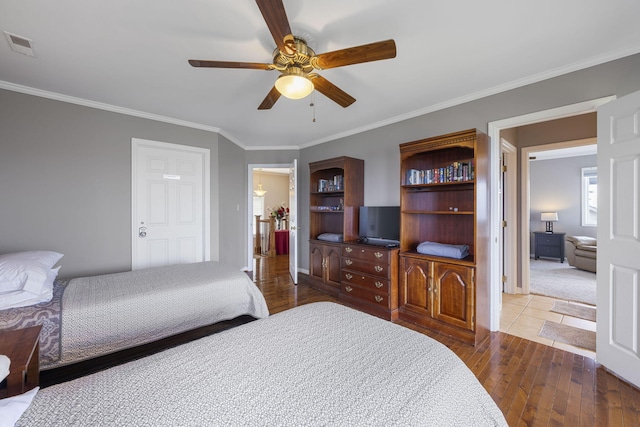 bedroom with a ceiling fan, visible vents, crown molding, and hardwood / wood-style flooring