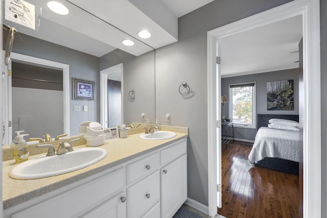 ensuite bathroom with a sink, double vanity, hardwood / wood-style floors, and connected bathroom