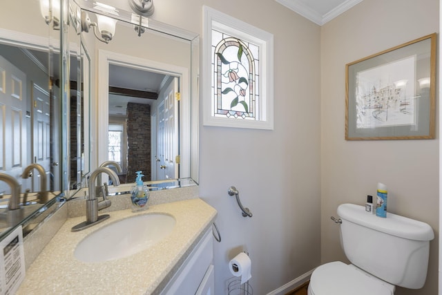 half bathroom with toilet, ornamental molding, vanity, and baseboards