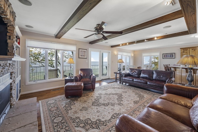 living area featuring visible vents, beamed ceiling, a stone fireplace, and baseboards