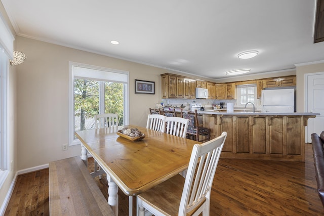 dining space featuring dark wood-type flooring, crown molding, and baseboards