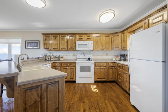 kitchen featuring brown cabinets, white appliances, light countertops, and a sink