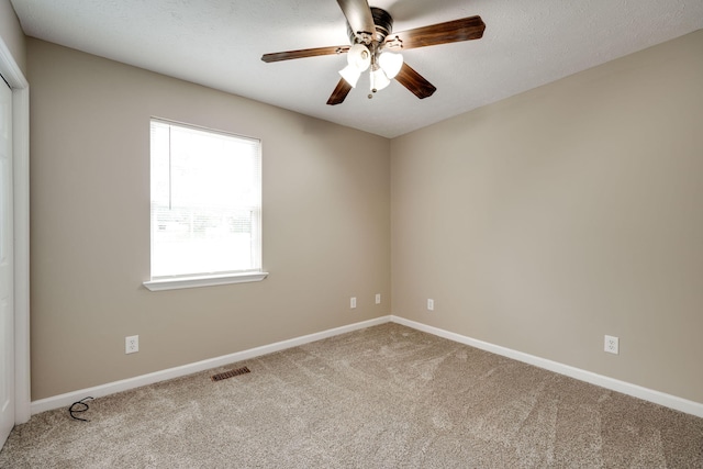 carpeted empty room with ceiling fan and a textured ceiling