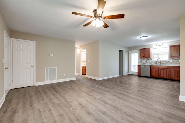 unfurnished living room featuring light hardwood / wood-style floors, sink, ceiling fan, and a textured ceiling