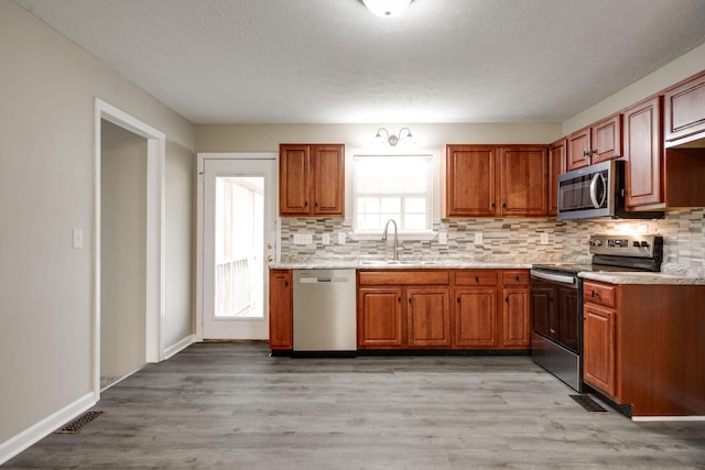 kitchen with light hardwood / wood-style flooring, stainless steel appliances, tasteful backsplash, and sink