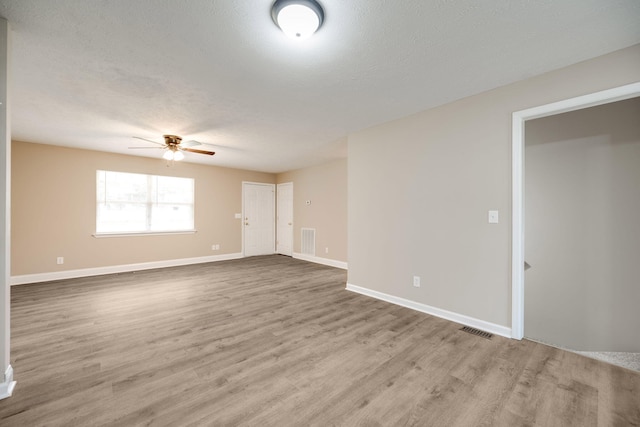 spare room featuring light wood-type flooring, a textured ceiling, and ceiling fan