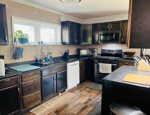 kitchen with appliances with stainless steel finishes, sink, and light hardwood / wood-style flooring