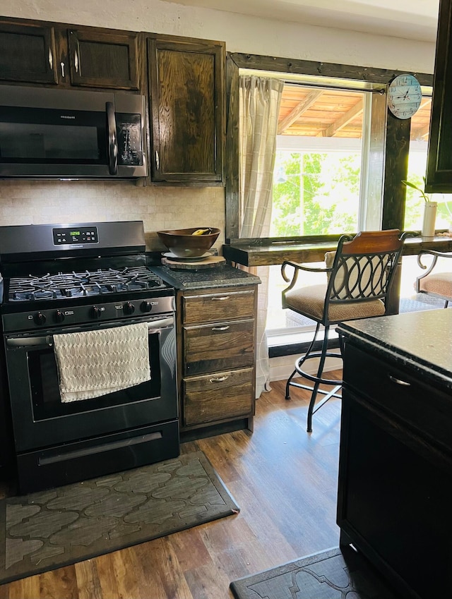 kitchen with dark brown cabinetry, stainless steel appliances, and light wood-type flooring