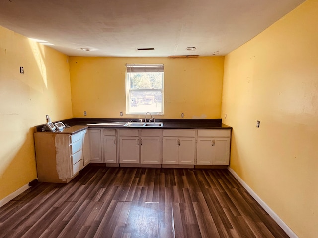 kitchen featuring dark hardwood / wood-style floors, kitchen peninsula, white cabinetry, and sink