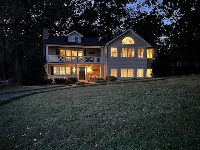 rear view of house featuring a balcony and a yard