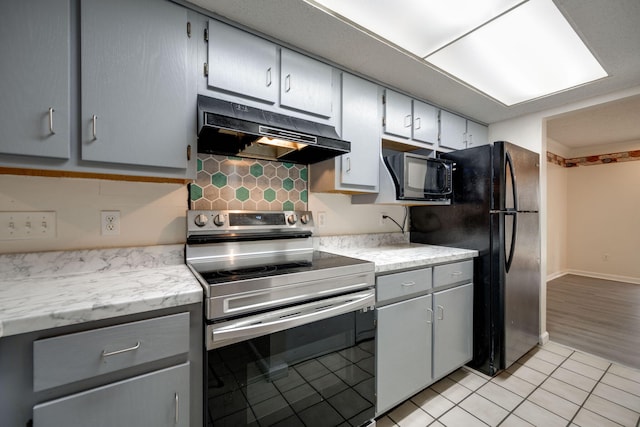 kitchen featuring black appliances, light hardwood / wood-style flooring, gray cabinetry, and backsplash