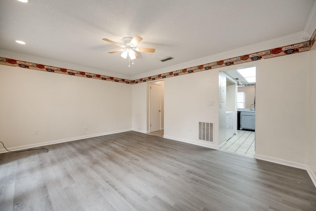 unfurnished room featuring a skylight, a textured ceiling, light wood-type flooring, and ceiling fan