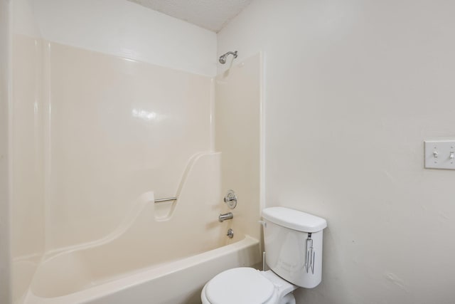 bathroom featuring toilet, a textured ceiling, and bathing tub / shower combination