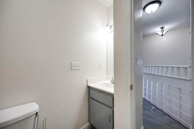 bathroom featuring vanity, a textured ceiling, wood-type flooring, and toilet