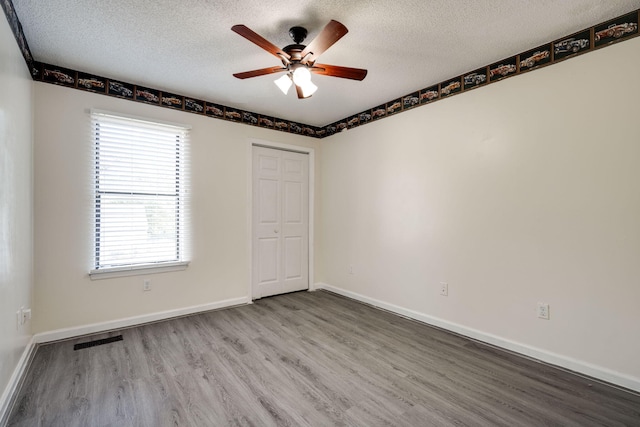 unfurnished room with a textured ceiling, wood-type flooring, and ceiling fan