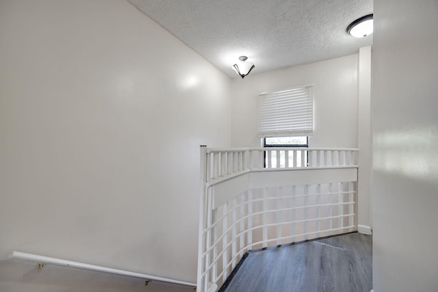 stairway with a textured ceiling and hardwood / wood-style floors