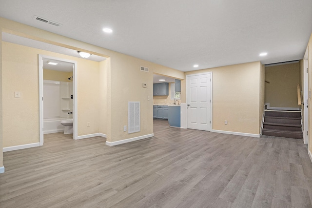 unfurnished living room with light hardwood / wood-style flooring and sink