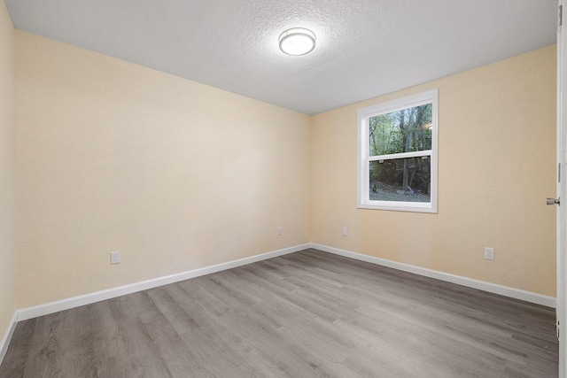 empty room featuring a textured ceiling and light hardwood / wood-style flooring