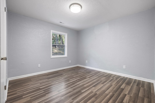 unfurnished room featuring dark wood-type flooring and a textured ceiling